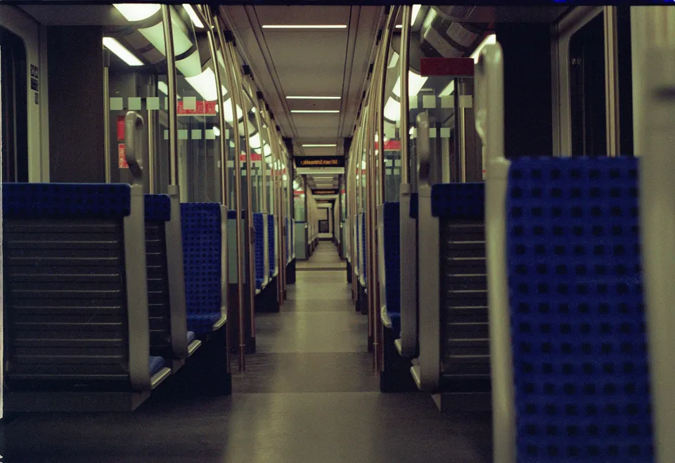 Blick durch den Gang eines U-Bahn-Wagens mit blauen Sitzen und Metallgriffen.