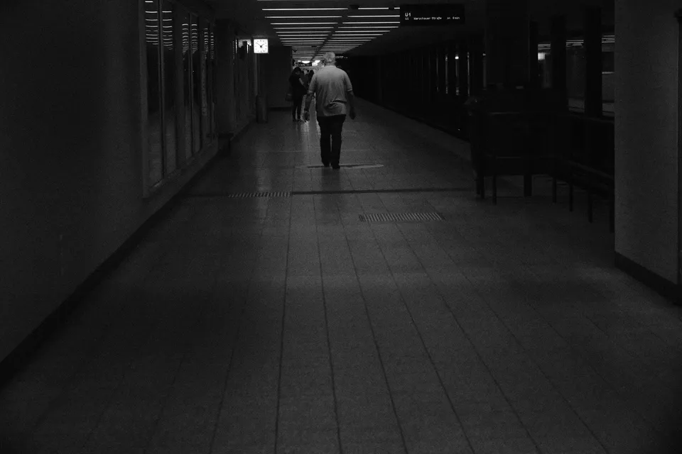 Eine Person geht in einer beleuchteten U-Bahn-Station entlang eines Bahnsteigs.