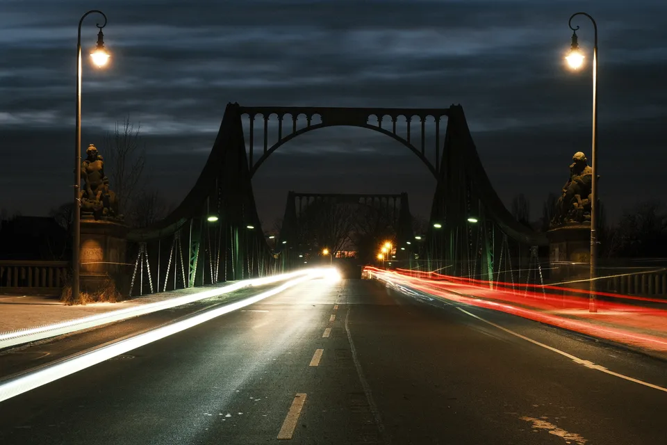 Eine beleuchtete Brücke bei Nacht mit langen weißen und roten Lichtspuren auf der Fahrbahn.