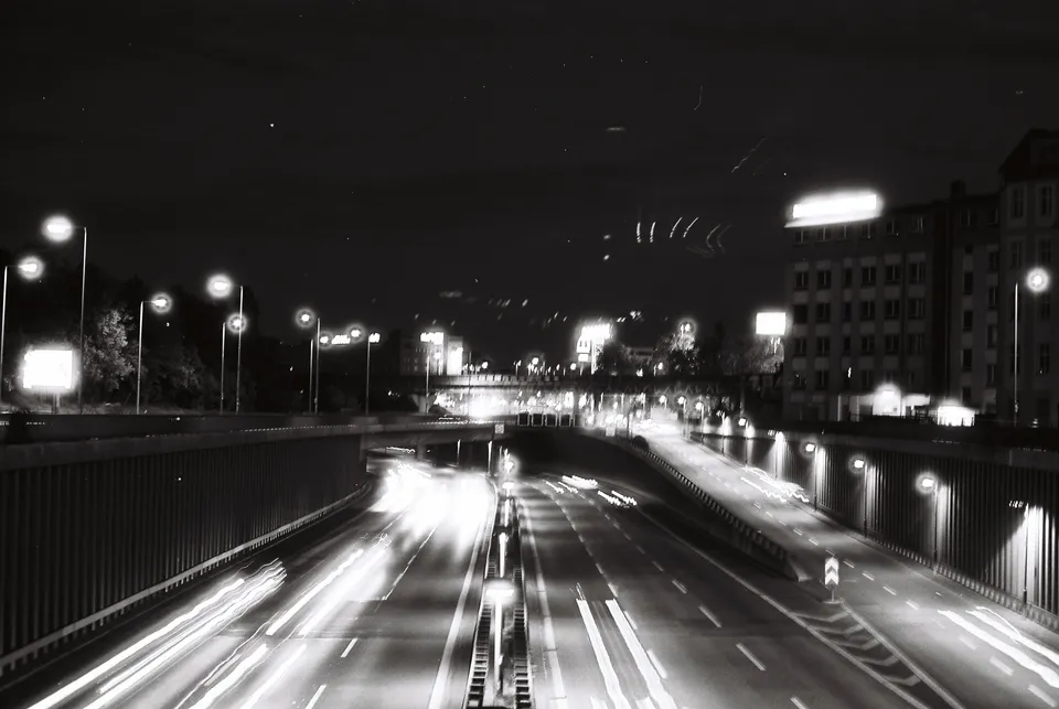 Langzeitbelichtung einer beleuchteten mehrspurigen Straße bei Nacht mit hellen Lichtstreifen.