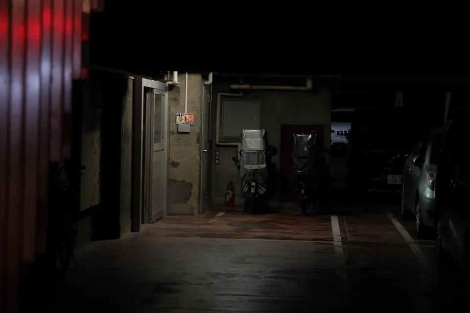 Eine beleuchtete Tiefgarage bei Nacht mit abgestellten Motorrädern und Autos.