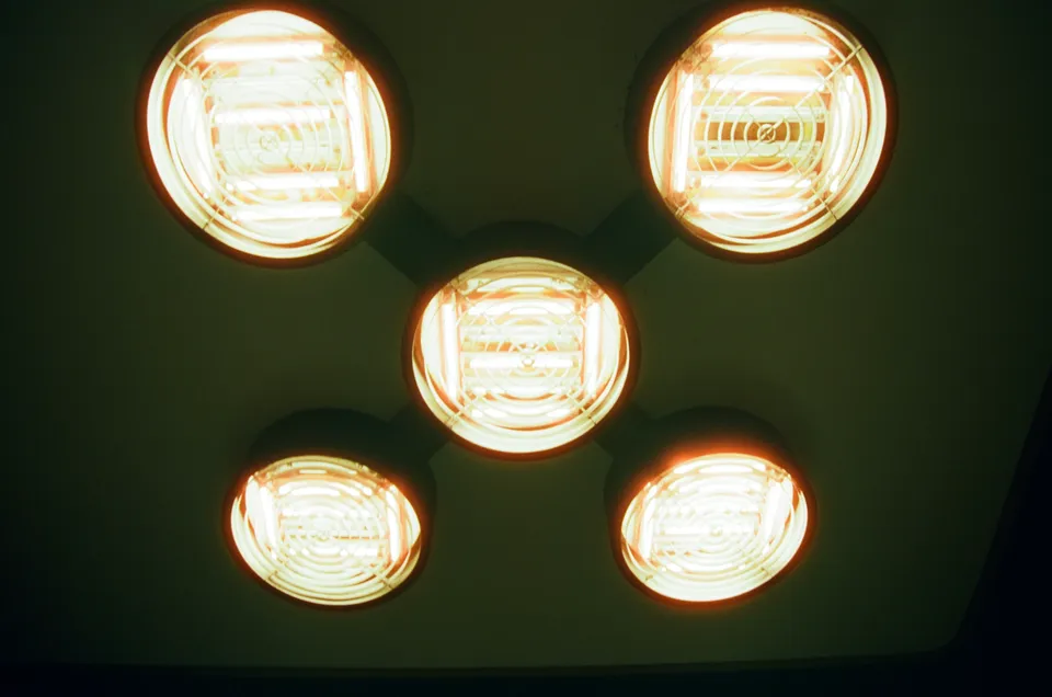 Eine Nahaufnahme von fünf hell leuchtenden, runden Lampen an einer dunklen Decke.