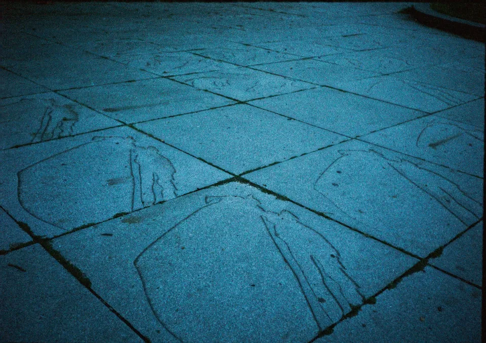Ein Boden aus bläulichen, quadratischen Fliesen mit eingravierten Figuren.