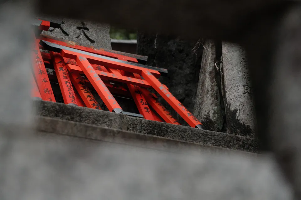 Ein Blick durch eine Öffnung auf mehrere rote Holztabletts, die in einer Steinnische stehen.