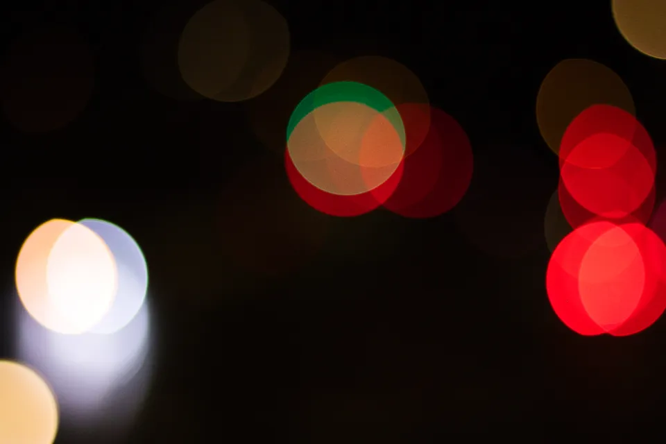 Abstrakte, farbige Lichtkreise in verschiedenen Rot-, Gelb- und Weißtönen vor schwarzem Hintergrund.