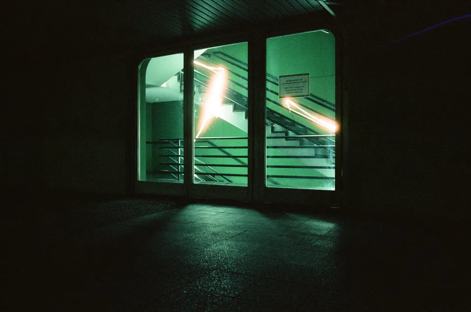 Lichtspuren auf den Glasscheiben einer beleuchteten Türanlage in einer dunklen Umgebung.