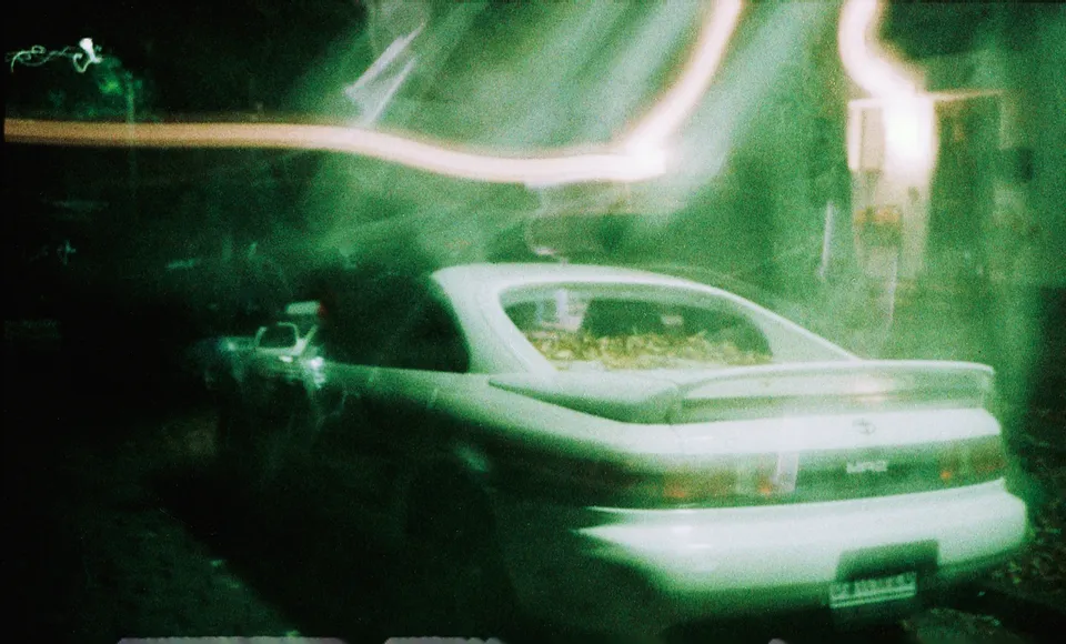 Ein parkendes Auto in einer nächtlichen Szene mit Bewegungsunschärfe und Lichtstreifen.