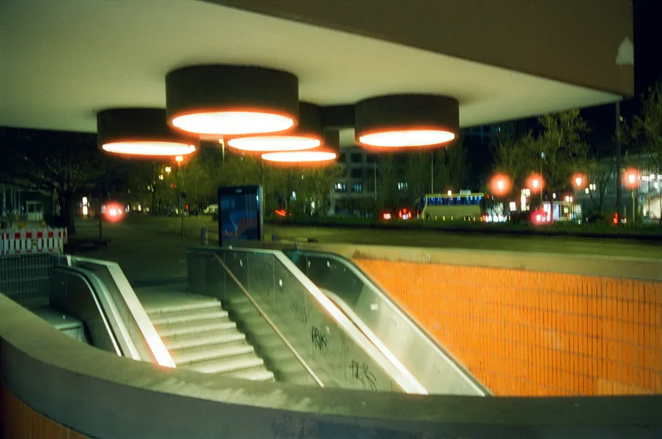 Ein beleuchteter Eingang zu einer Unterführung oder U-Bahn-Station bei Nacht.