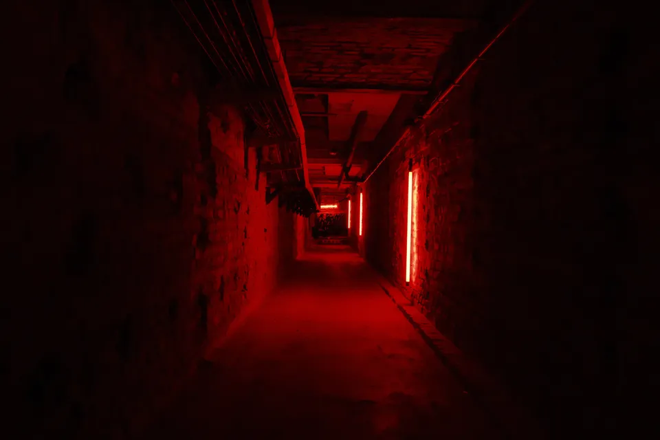 Ein schmaler, von rotem Licht beleuchteter Gang in einem Gebäude.