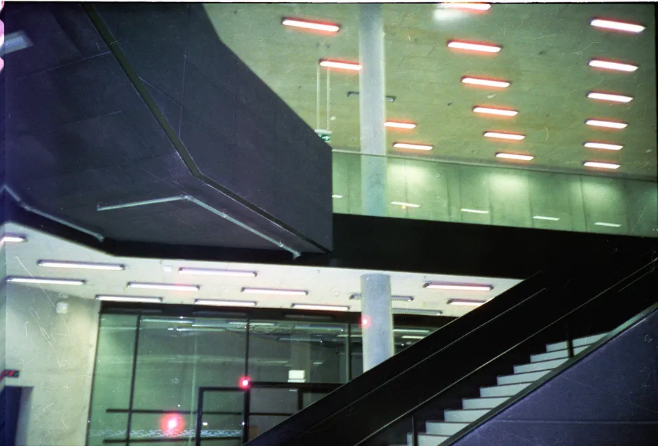 Ein Blick in ein modernes Gebäude mit Treppen, Glaswänden und geometrischen Lichtelementen.
