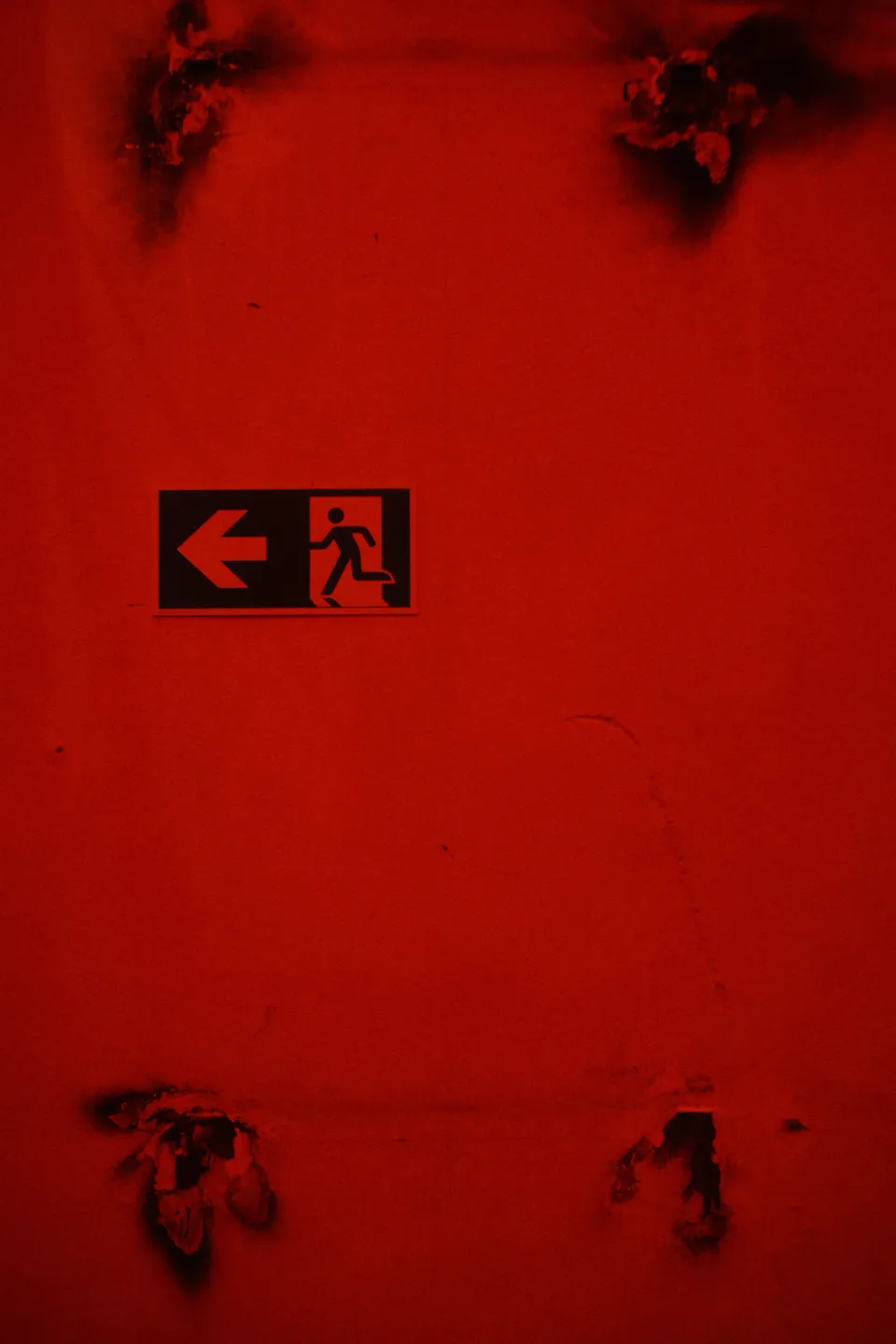 Ein Notausgangsschild an einer hellroten, fleckigen Wand.